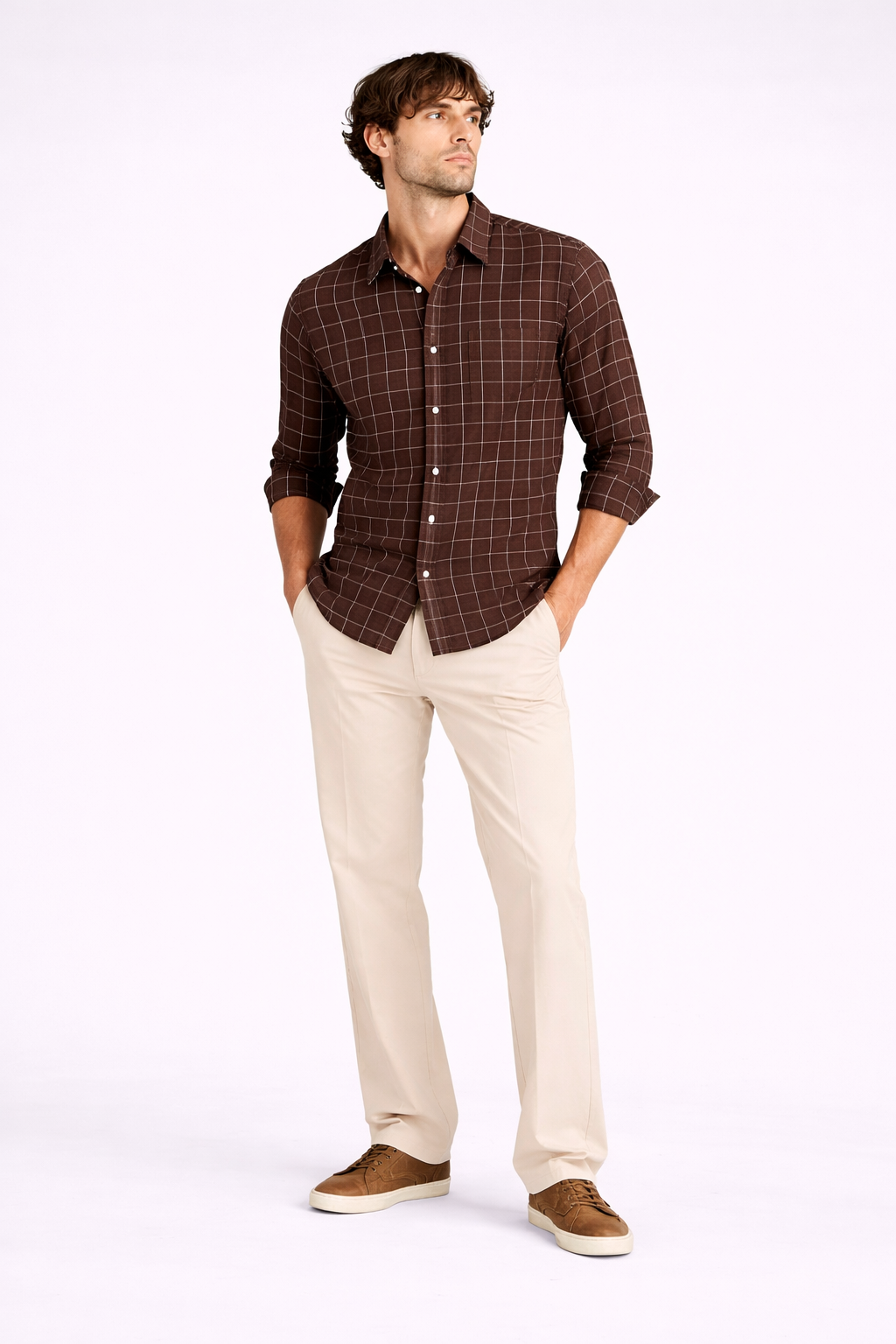 Man wearing a brown checkered shirt and beige pants on a white background